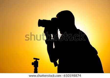 Man photographer with a camera at sunset