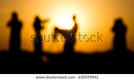 Blurred silhouettes of people with cameras at sunset