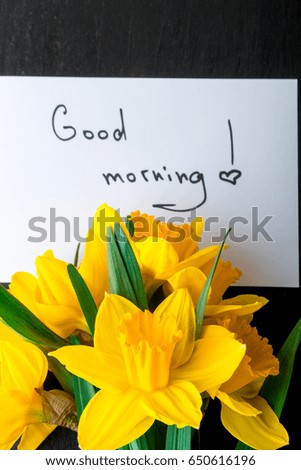 Bouquet of daffodil near card with good morning on black background. Top view. Copy space. Mothers day or Womens day. Greeting
