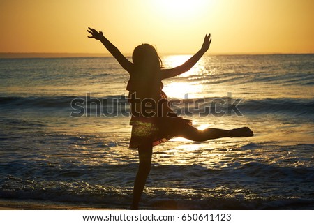 girl playing on the beach at sunset