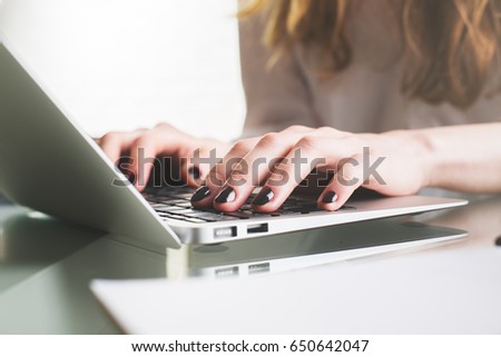 Close up and side view of lady's hands typing on laptop keyboard