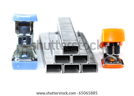 One blue and one orange stapler with staples on white background