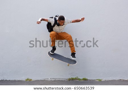 Full body portrait of young male skateboarder doing a trick outdoors