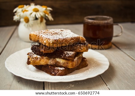 french toast with tea and daisies on wooden background Royalty-Free Stock Photo #650692774