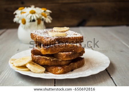 french toast with banana and daisies on wooden background Royalty-Free Stock Photo #650692816