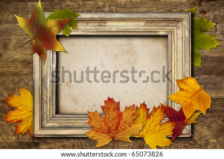 A vintage light frame and colored leaves on a wooden background
