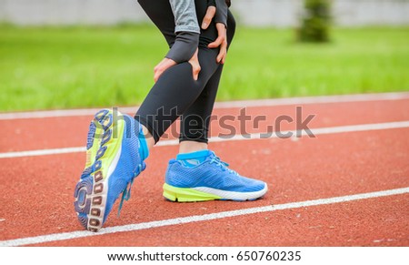 Athletic woman on running track has calf cramp and touching hurt leg during workout Royalty-Free Stock Photo #650760235