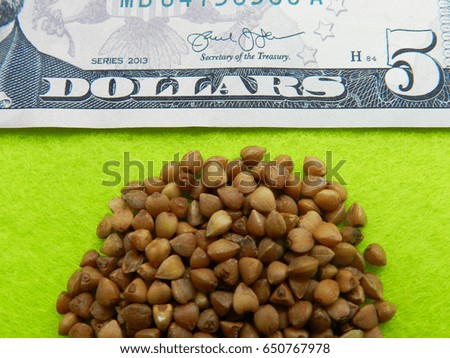Buckwheat grain on the five dollar banknote on the green background illustrated the high prices of the buckwheat