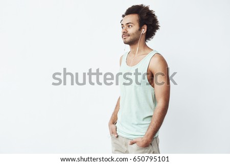Young african man smiling listening to music in headphones over white background.