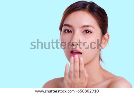 Beautiful Woman Face. Beauty Portrait. Beautiful Spa Woman Touching her Face. Perfect Fresh Skin. Pure Beauty Model Girl. Youth and Skin Care Concept. isolated on blue background.
