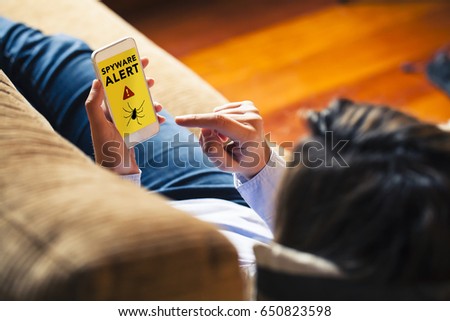 Woman using a mobile phone with a spyware alert in the screen.