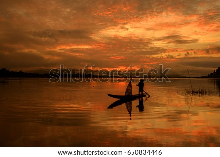 Silhouette of fishermen sailing on the sunrise.