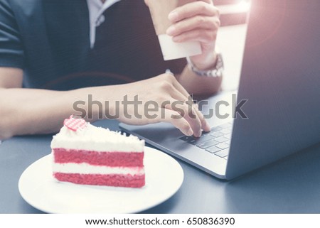 Man holding cup of coffee in hand and working with laptop. Generic design laptop is on the table. Sunlights effects.