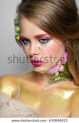 
Creative make-up beautiful portrait model bright girl flowers on face paint cosmetics make-up artist advertising gold fashion lips clause color