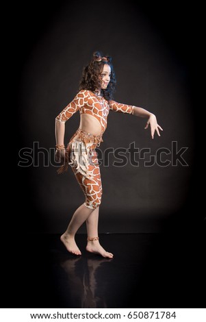 Cheerful brunette girl in orange dance suit dancing and posing on black background in studio