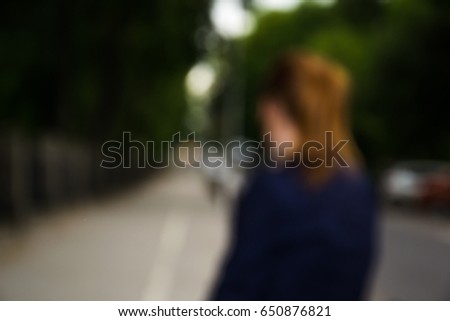 Blurry image of a womanf from back on the street