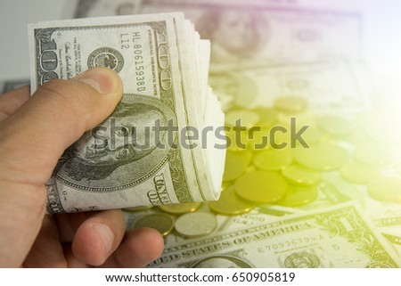 Close-up of man's hand holding hundred dollar bills. Money concept. Stack growing business. Lens flare in the background.