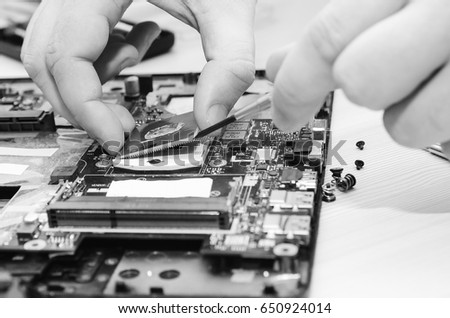 Repair laptops, close-up of hands and dismantled old computer. ?lack and white photography.