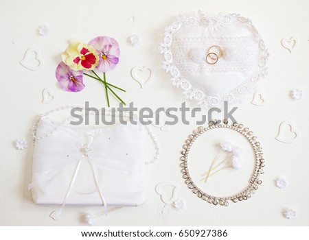 Bride accessories: rings, handbag, boutonniere, necklace. Wedding background. Top view.
