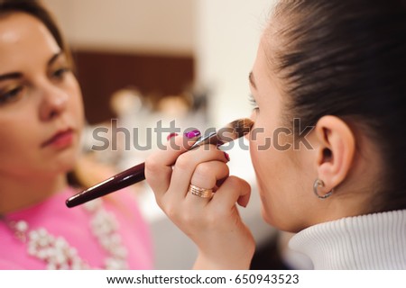 Make up artist doing professional make up of young woman.
