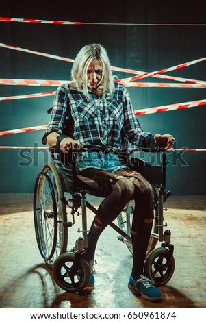 Pretty woman in the wheelchair on the dark background.