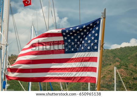The US flag in the wind next to the yachts