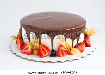 Birthday cake in chocolate with strawberries, blueberries and physalis on white background. Picture for a menu or a confectionery catalog.