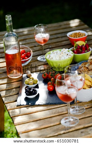 holiday summer brunch party table outdoor in a house backyard with appetizer, glass of rose wine, fresh drink and organic vegetables  