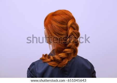 Beautiful girl with long red hair, braided with a French braid, in a beauty salon. Professional hair care and creating hairstyles. Royalty-Free Stock Photo #651045643