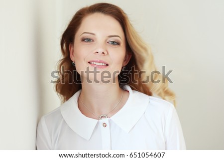 beautiful woman with blond hair in white shirt, smiling on camera Royalty-Free Stock Photo #651054607