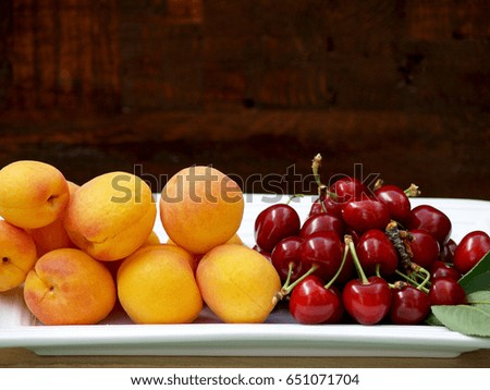 fresh red cherries and apricots on a tray