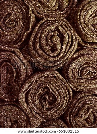 Pile of rolled up chocolate brown colored blankets, vertical photo for background and texture 