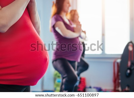 Group of pregnant woman in yoga tree pose balancing on one foot 