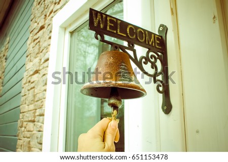 A large bell next to the door, replacing the doorbell. the bell Welcome. Ring the bell.