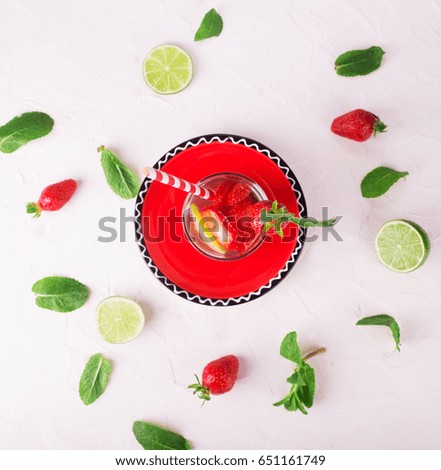 Fresh lemonade with strawberries, lime and mint in a tall glass on a white background