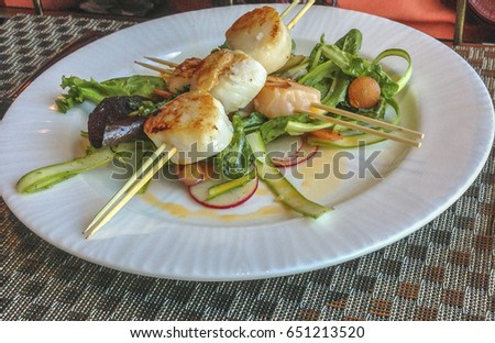Picture of Sea Scallops on a skewer over a bed of greens