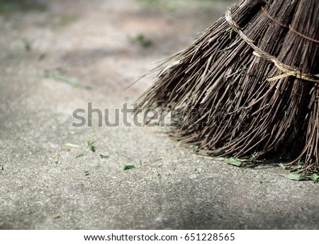old used hand made craft work broomstick made of long dried brown coconut leaf for outdoor use picture taken with selective focus blur dirty ground floor background