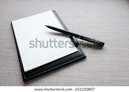White paper and pen on the leather board. Hotel notepad.