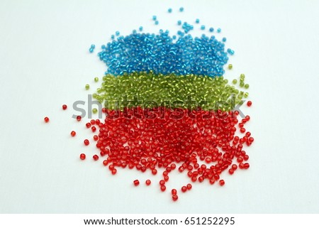 BLUE, GREEN AND RED SEED BEADS HORIZONTALLY ON WHITE BACKGROUND