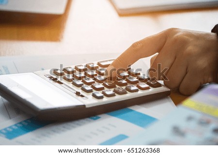 A business woman analyzing investment charts at his workplace and using his laptop ,stock chart , cellphone, close up vintage stlye