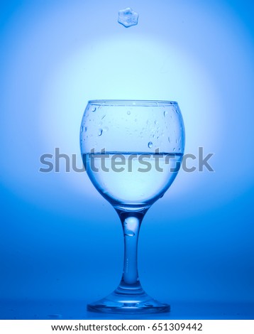 wine glass with water and ice snowflake on a blue background.