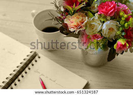 Blurred cup of coffee with flowers in vase and old book