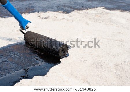 Worker covered surface, bitumen primer for improving adhesion during surfacing,  rolled waterproofing, during the installation of isolation on industrial or household objects. Waterproofing.Copy space Royalty-Free Stock Photo #651340825