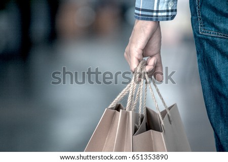 Man hand holding shopping bags on the street in the shopping mall in vintage color tone