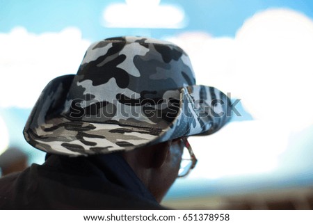 A tourist wearing a soldier design hat at an airport.