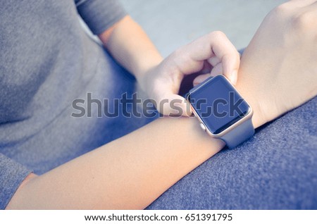 Close-up. Image of a woman with smart-watch on the wrist. Flare, orange lighting, Technology and sports. Background of cement floor simulating court and parking lot. Wearable technology.