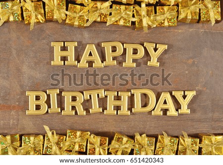 Happy birthday golden text and golden gifts on a wooden background