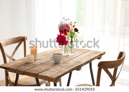 Beautiful flowers in vases as floral decor on wooden table