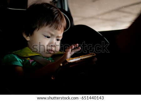 asian child playing smartphone on car  / dark tone color