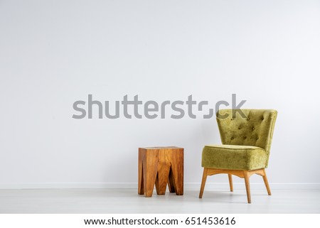 Stylish green armchair on the white wall